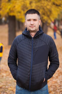 Close up portrait of a young man on the background autumn park clipart