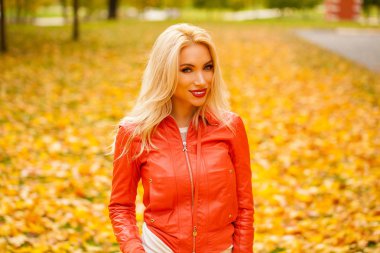 Mutlu gülümseyen güzel sarışın genç kadın mavi kot pantolon ve kırmızı ceket, sonbahar sokak açık havada portresi