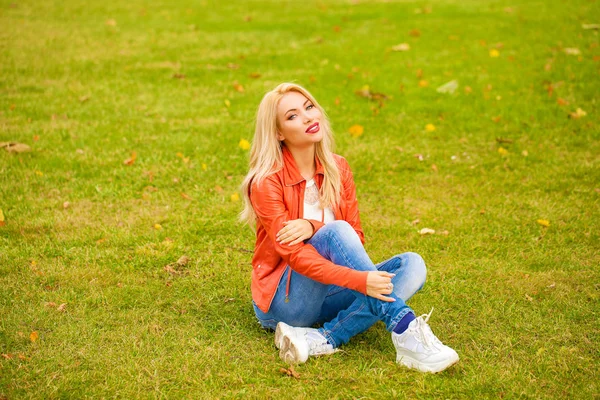 若いですブロンド女性で青いジーンズで秋の公園 — ストック写真