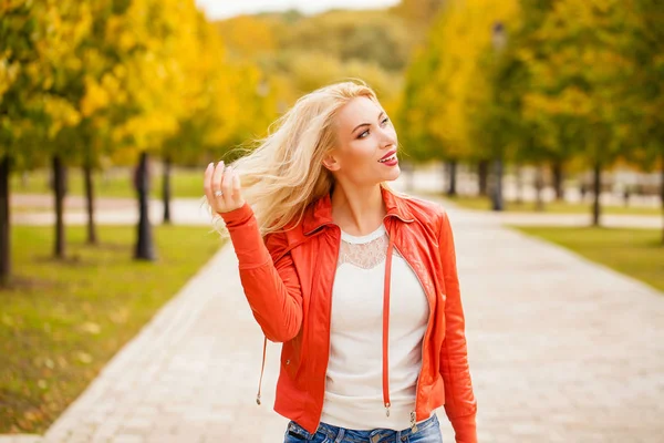 愉快的微笑美丽的年轻金发女子在蓝色牛仔裤和红色外套 秋季街户外的纵向 — 图库照片