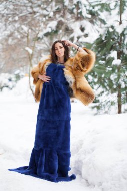 Tam uzunlukta kürk giyen genç güzel zarif esmer kadın portresi. Moda kız kış street yürüyüş.