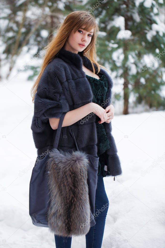 Full length portrait of young beautiful elegant brunette woman wearing fur coat. Fashionable girl walking at the street at winter.