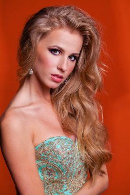 Sarı saçlı ve mükemmel makyaj, kırmızı turuncu duvar studio arka plan ile mutlu güzel genç modeli