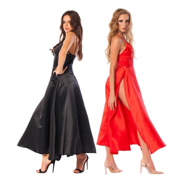 İki seksi sarışın ve esmer modelleri. Uzun elbise, beyaz duvar arka plan üzerinde poz bir güzel kadınların tam uzunlukta 