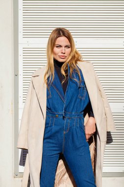 Mutlu güzel sarışın genç kadın mavi kot pantolon ve bej bir palto, sokak açık havada portresi