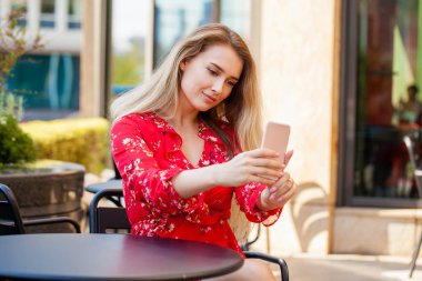 Genç güzel esmer elbise kendini sokakta bir yaz kafede oturan bir cep telefonu üzerinde resim çekme