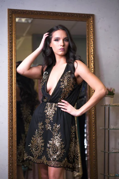 ショールームで新しいドレスをしようとしている若い女性 ファッションと選択の概念 黒のセクシー ドレスでブルネットのモデル — ストック写真