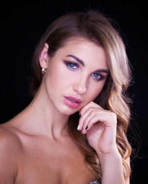 Siyah arka planda uzun sarı saçlı güzel bir mankenin yakın plan portresi.