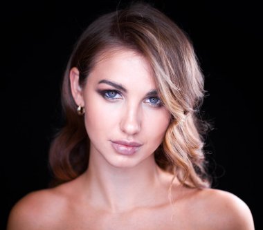 Siyah arka planda uzun sarı saçlı güzel bir mankenin yakın plan portresi.