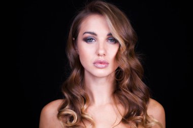 Siyah arka planda uzun sarı saçlı güzel bir mankenin yakın plan portresi.