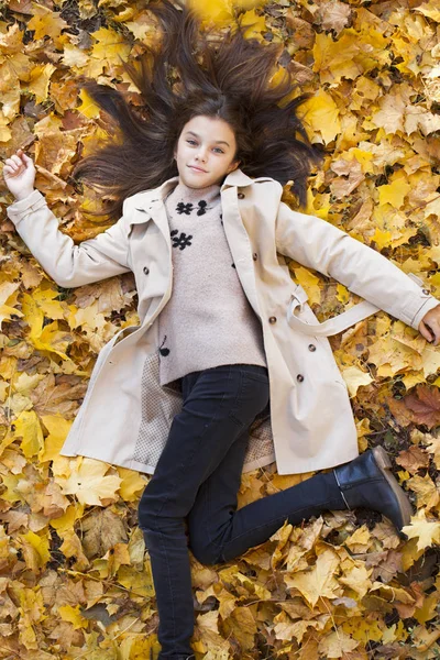 美丽的小女孩躺在公园的叶子在美丽的秋天天 — 图库照片