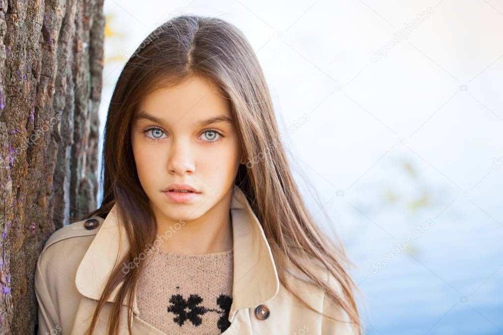 Portrait of a beautiful young brunette little girl, autumn park outdoors