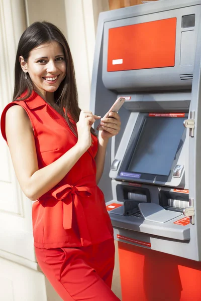 Молодая Счастливая Брюнетка Красном Платье Снимает Деньги Кредитной Карты Банкомате — стоковое фото