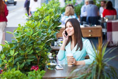 Zarif kız açık kafede kahve fincan ile dinlenme süre diyen birileri uzun siyah saçlı. Açık ciddi fashionista kadın fotoğrafı 