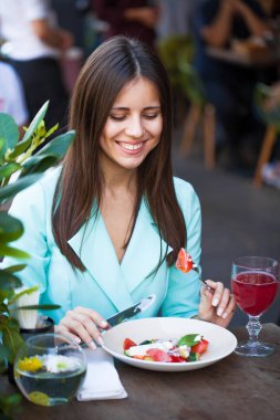 Genç güzel esmer kadın bir kafede yaz sokak açık havada kahvaltı yapıyor