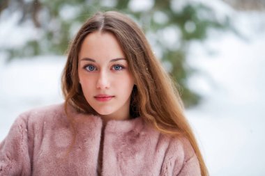 Kış park üzerinde poz kürk ceket genç güzel esmer kadın. Şık sıcak giysiler giyen modeli.