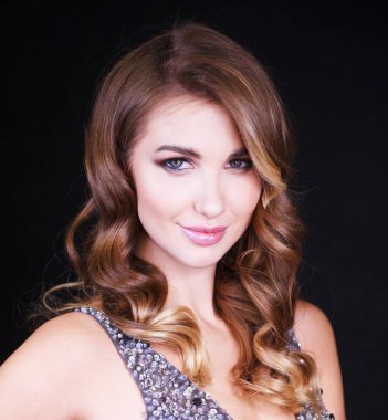 Siyah arka planda uzun sarı saçlı güzel bir mankenin yakın plan portresi.