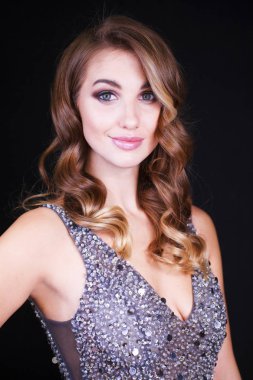 Siyah arka planda uzun sarı saçlı güzel bir mankenin yakın plan portresi.