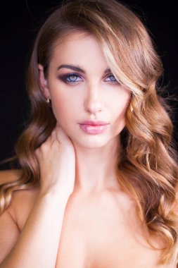 Siyah arka planda uzun sarı saçlı güzel bir mankenin yakın plan portresi.