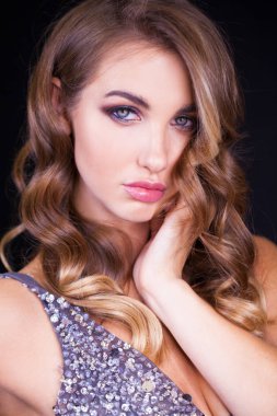 Siyah arka planda uzun sarı saçlı güzel bir mankenin yakın plan portresi.