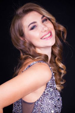 Siyah arka planda uzun sarı saçlı güzel bir mankenin yakın plan portresi.