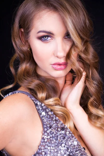 Siyah arka planda uzun sarı saçlı güzel bir mankenin yakın plan portresi.