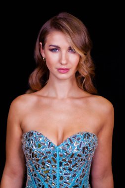 Makyaj. Güzel sarışın kadın seksi turkuaz elbise. Sağlıklı uzun kıvırcık saçlar. Siyah arka plan üzerine izole