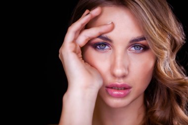 Siyah arka planda uzun sarı saçlı güzel bir mankenin yakın plan portresi.