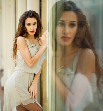 Portre yakın çekim bej elbise genç güzel esmer kadın, bir vitrin Aynasal Yansıma