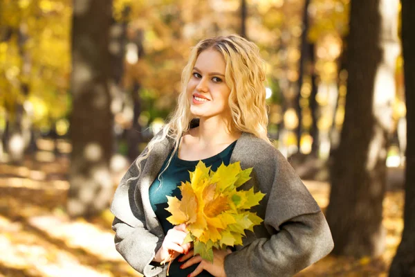 在秋天街头的背景上的灰色外套年轻金发美女的画像 — 图库照片