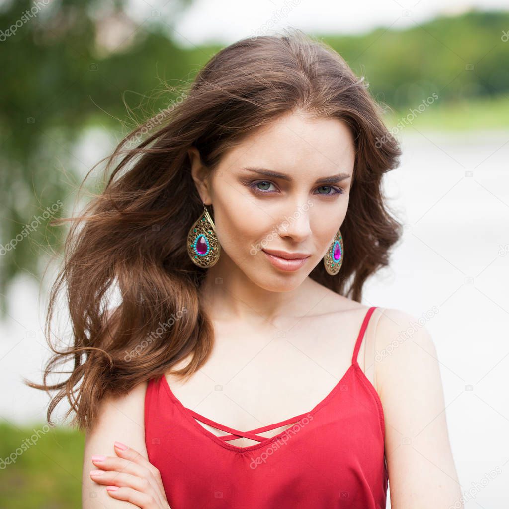 Closeup portrait of a young beautiful brunette woman on summer background