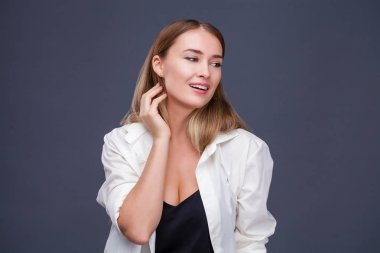 Mutlu sarışın model. İzole gri arka plan üzerinde beyaz gömlekli güzel genç kadın portresi