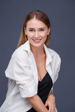 Mutlu sarışın model. İzole gri arka plan üzerinde beyaz gömlekli güzel genç kadın portresi