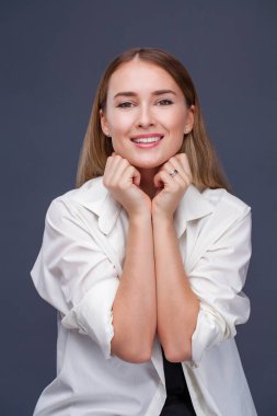 Mutlu sarışın model. İzole gri arka plan üzerinde beyaz gömlekli güzel genç kadın portresi