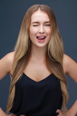 Mutlu sarışın model. Gri arka plan üzerinde izole elbiseli güzel genç kadın portresi