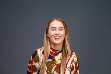 Mutlu sarışın model. Gri arka plan üzerinde izole elbiseli güzel genç kadın portresi