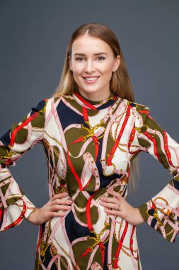 Mutlu sarışın model. Gri arka plan üzerinde izole elbiseli güzel genç kadın portresi