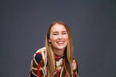 Mutlu sarışın model. Gri arka plan üzerinde izole elbiseli güzel genç kadın portresi