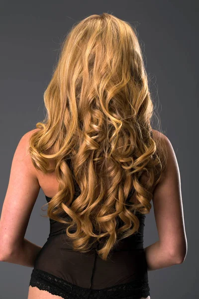 Female Long wavy blonde hair, rear view, studio wall background