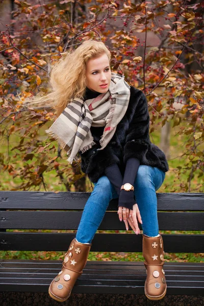 ミンクの毛皮コート通り秋に屋外 ベンチに座っての完全な長さの若い ブロンドの女性の肖像画 — ストック写真