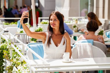 Güzel, esmer gülümseyen bir akıllı telefon ile bir fotoğrafını alın. selfie, yaz açık havada