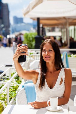 Güzel, esmer gülümseyen bir akıllı telefon ile bir fotoğrafını alın. selfie, yaz açık havada
