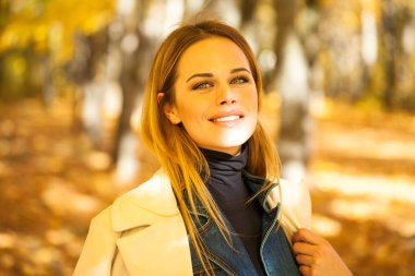 Sonbahar sokak bir arka plan üzerinde gri paltolu bir genç güzel sarışın kadın portresi