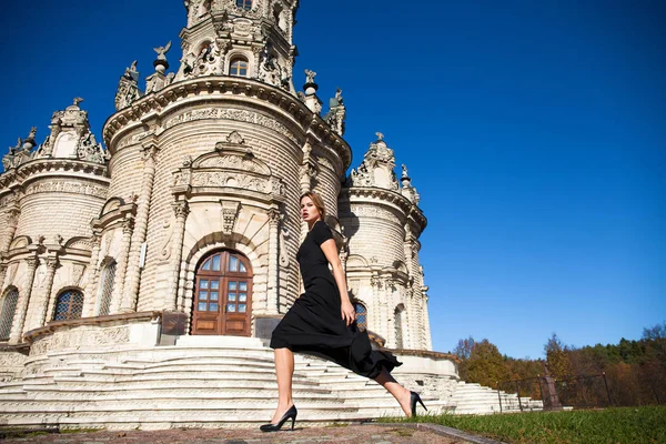 教会の背景に黒のドレスの若い美しい女性 — ストック写真