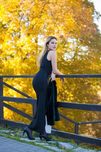 完全なボディ 秋の公園の長い黒のドレスの若い美しいブロンドの女性 — ストック写真