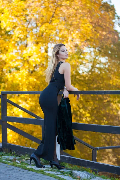 年轻美丽的金发碧眼的女人穿着黑色长裙在秋天公园 — 图库照片