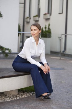 Bir parkta bir bankta oturan bir tam uzunlukta genç güzel iş kadın portresi