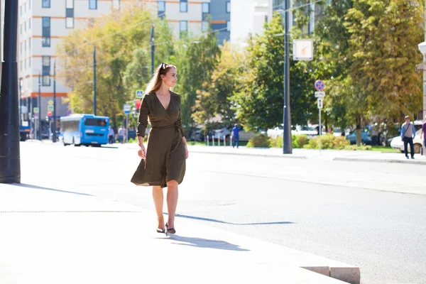 Tam büyüme portre, genç güzel sarışın kadın koyu yeşil elbise sokakta yaz açık havada yürüyüş