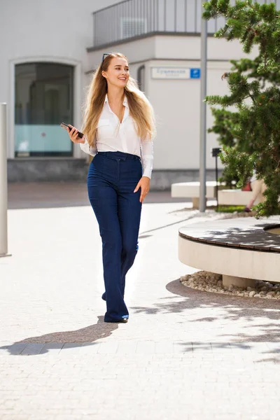 一个身穿蓝色牛仔裤和白衬衫的年轻漂亮的女商人的画像 — 图库照片