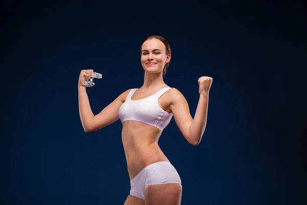 The strength of a woman in her weakness. Weight loss and healthcare concept. Strong beautiful brunette girl in white fitness clothing
